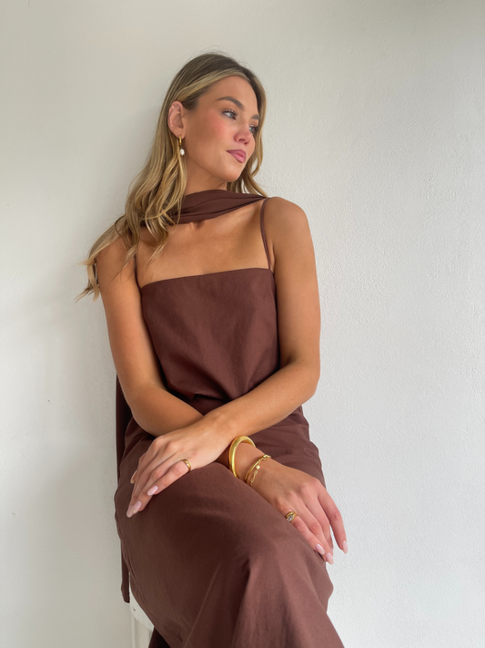 By Nicola Ivy maxi dress in chocolate brown cotton-linen with straight neckline, side slit, column style and chiffon neck tie, ideal for weddings and summer events.