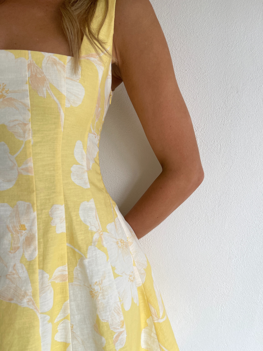By Nicola Milly mini dress in amarilla flor yellow floral print in cotton linen with  straps and flowy hem, perfect for daytime events and summer occasions. Exclusive to Coco & Lola